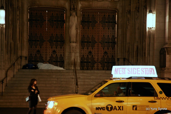 Надпись на такси: Вэстсайд стори. Есть такой фильм.
В кадре романтическая история: женщина ждёт такси и мужчина спит на земле. Нью-Йорк, CША