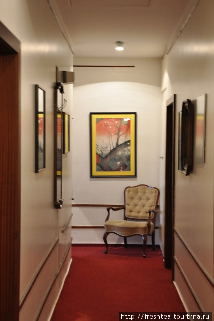 Строгому коридору  добавили шарма репродукции картин и манерное кресло. Вена, Австрия