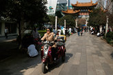 Популярное средство транспорта в Куньмине. На заднем плане, в белых халатах — уличные массажисты. Прямо посреди сквера стоят стулья, мануалы предлагают прохожим свои услуги.