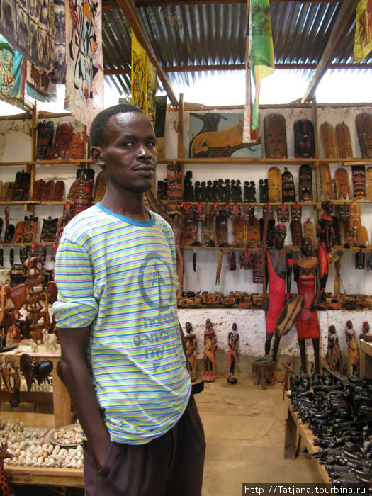 продавец сувениров в придорожном павильоне Кения