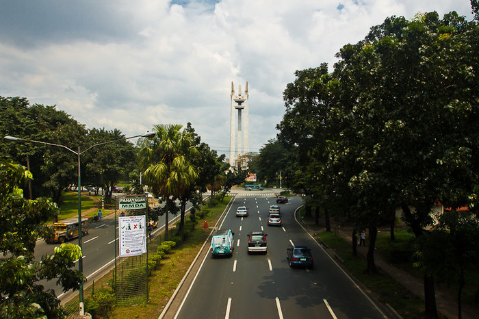 Кесон авеню, вдалеке высится монумент, а за ним — государственный университет Кесон-Сити, Филиппины