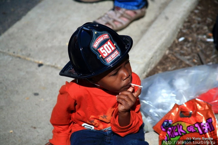 Малчик в шапке пожарного сосёт леденец. Манассас, CША