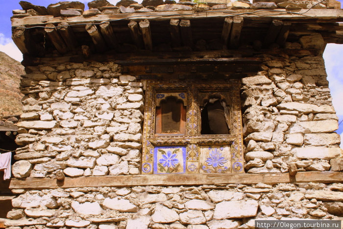 Резные окна на каменной стене Мананг, Непал