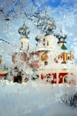 Сквозь узоры морозного стекла трапезной, где обедал царь Иван Грозный, проглядывает Успенский собор Тихвинского монастыря.