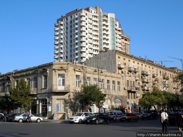 Новый дом возвышается над старыми домами Баку, Азербайджан
