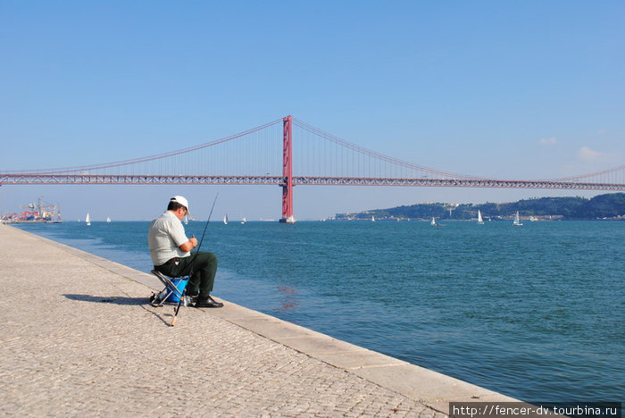 Рыбак на фоне моста — самая популярный вид с набережной Лиссабон, Португалия