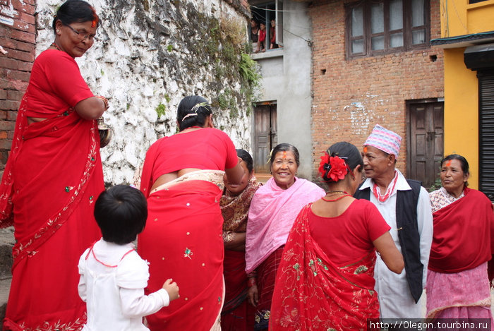 Женщины в красных одеждах спускаясь по лестнице рисовали тики на лбах людей Киртипур, Непал