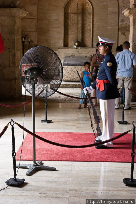 У входа стоит почетный караул из одного солдата, которого обдувает вентилятор. Стоять не двигаясь в полном обмундировании при такой жаре (даже с вентилятором) — уже само по себе подвиг. Провинция Санто-Доминго, Доминиканская Республика