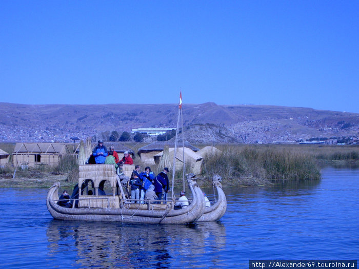 Туристы катаются на тростниковых лодках вокруг островов. Под перуанским влагом — местные индейцы патриоты. Озеро Титикака, Перу