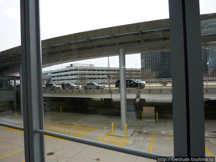 Вид на многоэтажную парковку в аэропорту О’Хара через стекло  окна  терминала. Хьюстон, CША