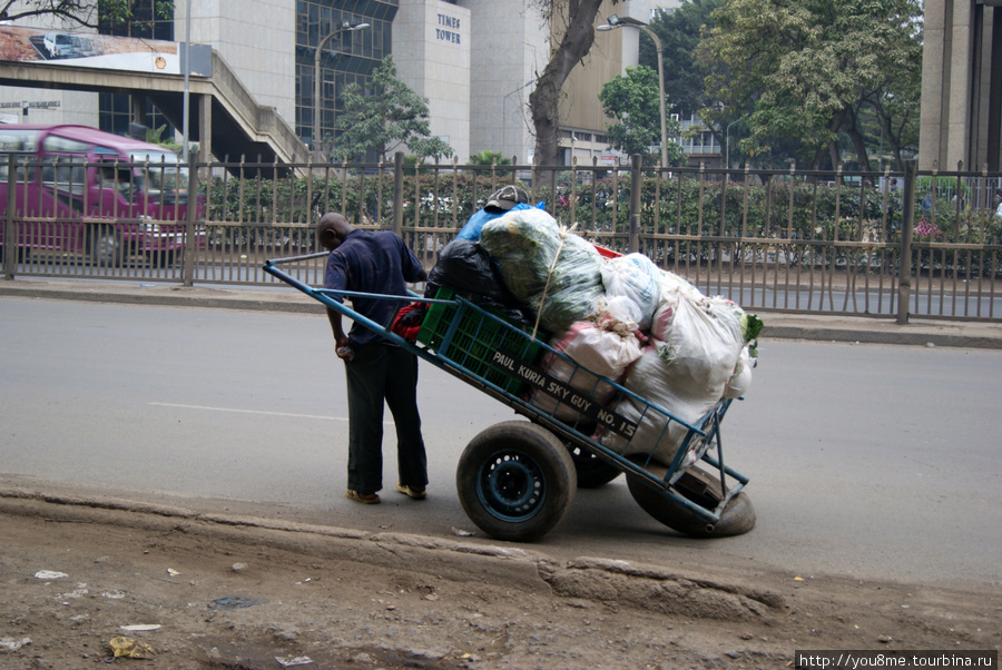 одновременно с легковыми машинами на дорогах рикши с тяжелогружеными тележками Найроби, Кения