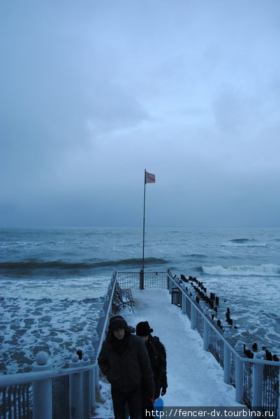 Туристов, желающих посмотреть на море с пирса не остановит никакой ветер.